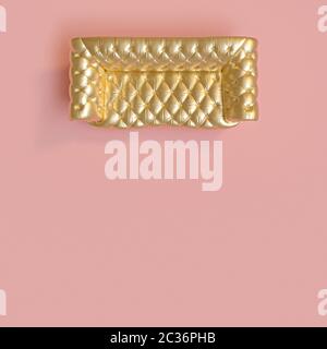 top view of a classic gold-colored tufted sofa on a pink background. 3d render image