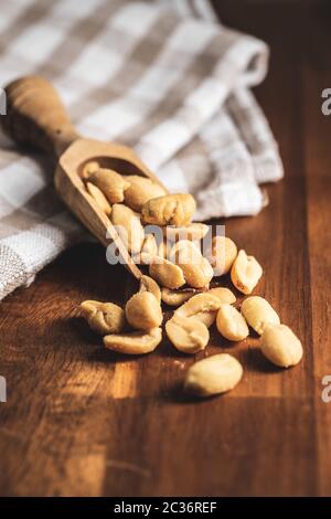 Roasted salted peanuts. Crispy nuts in scoop on wooden table. Stock Photo