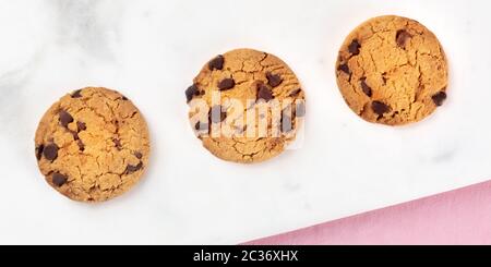 Chocolate chip cookies panorama, shot from above on a white marble and pink background Stock Photo