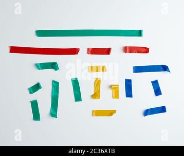 set of torn multicolored rubber pieces of electrical tape glued to a white background, close up Stock Photo