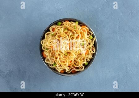 Instant noodles with carrot, scallions, and a sauce, a vegetable soba bowl, shot from above on a slate background Stock Photo