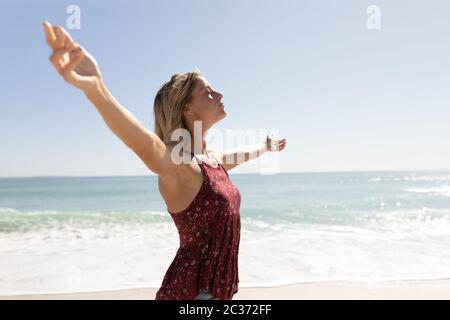Young caucasian woman raising arms on the beach Stock Photo