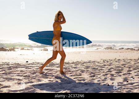 Young caucasian woman holding surf board on beach Stock Photo
