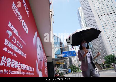 Beijing, China. 18th June, 2020. A woman walks past an advertisement billboard marking the listing of JD.com in Hong Kong, south China, June 18, 2020. JD.com started trading on the Hong Kong market Thursday as the third U.S.-listed Chinese mainland company that completed a secondary listing in Hong Kong. Credit: Wang Shen/Xinhua/Alamy Live News Stock Photo