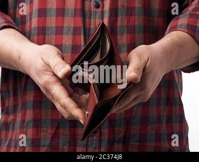 man in a red plaid shirt holds an empty leather brown wallet, concept of poverty and economic crisis Stock Photo