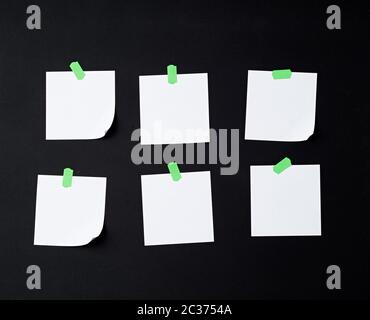 set of square white blank sheets of paper glued with green sticky paper on black background Stock Photo