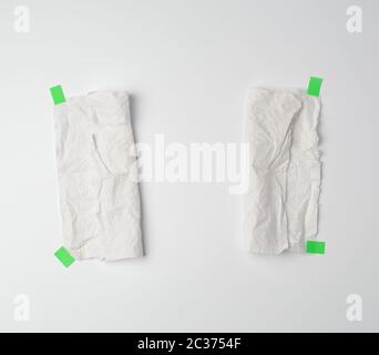 crumpled dirty white piece of paper towel glued with green paper velcro on a white background, place for text Stock Photo