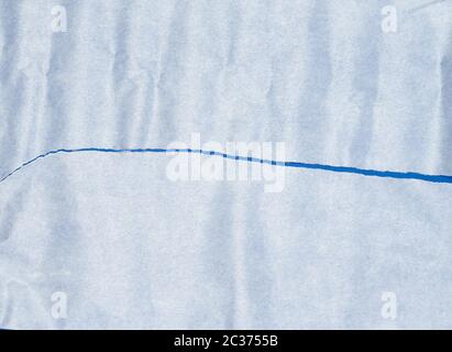 torn piece of white parchment paper on a blue background, close up Stock Photo
