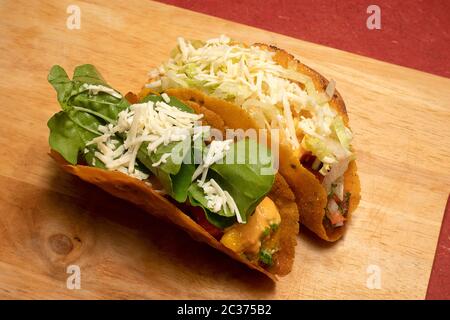 MEXICAN TACOS WITH REFRIED BEANS, MANGO SALSA, TOMATO SALSA, CHIPOTLE SAUCE, TOPPED WITH LETTUCE, CHEESE, ROQUETTE  LEAVES Stock Photo