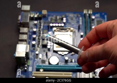 Drawing thermal paste on the computer processor. Installing a cooling system on a CPU processor Stock Photo