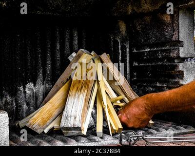 Preparation of a BBQ - wood piled up - starting the fire with a match Stock Photo