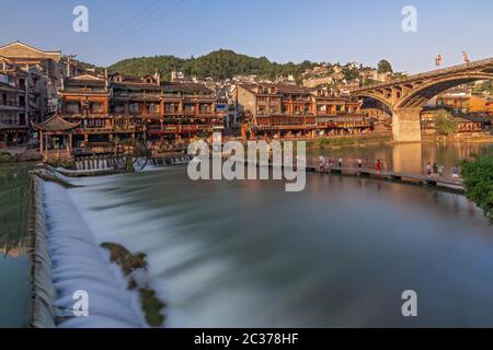 Feng Huang, China -  August 2019 : Long time exposure of the small artificial  cascade waterfall on the Tuo Jiang riverin the Old Town of Fenghuang kn Stock Photo