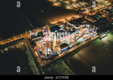 Santa Monica Pier at Night in super colourful lights from Aerial Drone perspective in Los Angeles, California Stock Photo