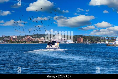 A full ferry pulling out of Halifax harbor and crossing blue water Stock Photo