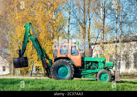 Old russian tractor with loader left at the trees Stock Photo