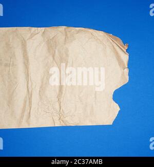 torn brown sheet of paper on a blue background, full frame, close up Stock Photo