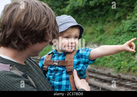 Father and son (2 years old) at Alresford Station on the Mid-Hants Railway, Hampshire, England, UK.  Excited little boy pointing at a train Stock Photo