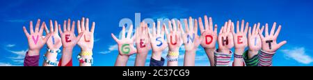 Kids Hands Holding Colorful German Word Viel Gesundheit Means Stay Healthy. Blue Sky As Background Stock Photo