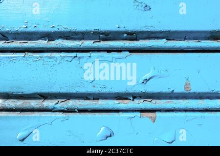 Background of old metal sheet with peel paint texture surface. Painted metal roller shutters door with peeling paint dirty blue hue. Grungy background Stock Photo