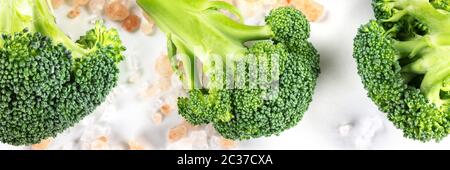 Broccoli florets close-up panoramic flat lay shot on a white background with pink Himalayan salt Stock Photo