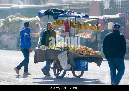 Essaouira, Morocco, Feb 2019: Old muslim man selling lemons and fruits from cart at traditional street market in Morocco. Moroccan old town medina Stock Photo