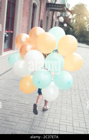 Unrecognizable kid running with balloons Stock Photo