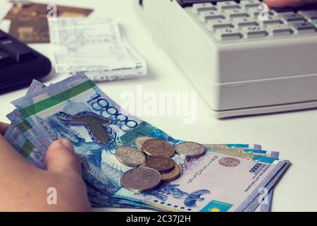 Tenge at the cashier accountant in the hands of the workplace in the office. The cashier counts the money KZT in the workplace in Kazakhstan. Salary i