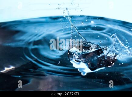 Water splash. Ice cubes falling into the blue water. Splash of ice water. Water splashes from falling ice cubes Stock Photo