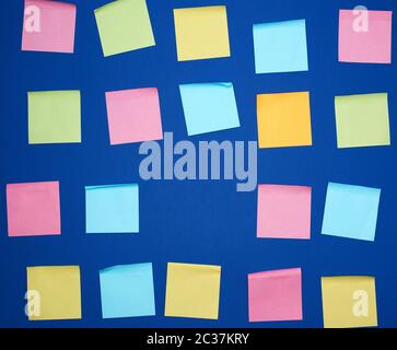 many glued square multi-colored blank stickers on a blue background, close up Stock Photo