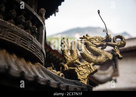 Close up of a small golden dragon sculpture decoration on a wooden roof, Buddhist Temple in Huashan town, Shaanxi Province, China Stock Photo