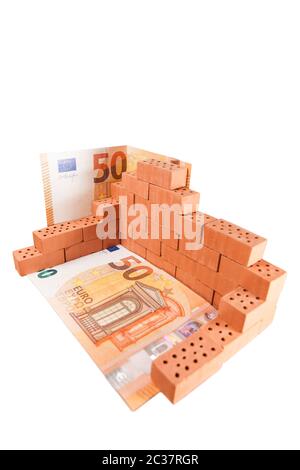 Wide-angle close-up of wall-stacked clay building block stabilized with 50-euro bills and isolated on white. Stock Photo