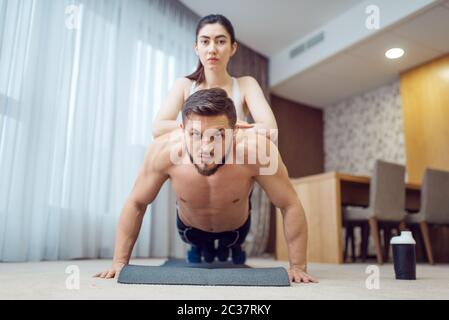 Morning fitness training of love couple at home. Active man and woman in sportswear doing push up exercise in their house, healthy lifestyle, physical Stock Photo