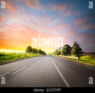Asphalt road among fields under sky Stock Photo - Alamy