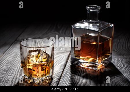Backlit glass of whiskey with ice on wooden table Stock Photo