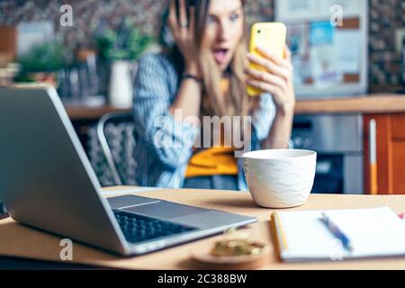 Distance learning online education and work. Business woman having a facetime video call. Surprised girl working from home office kithcen and drinking Stock Photo