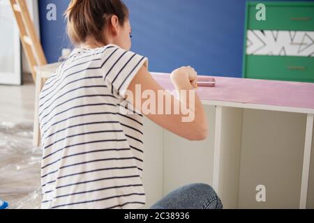 Young woman repainting old furnitures Stock Photo