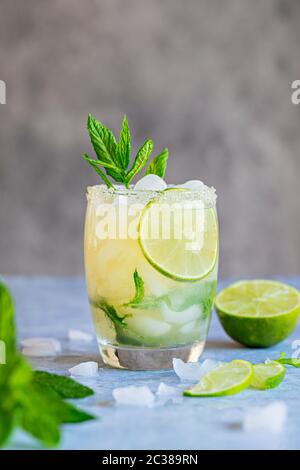 A fresh Mojito drink with mint leaves and lime and crushed ice. On a gray background. Copy space room for text above the drink. Stock Photo