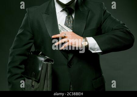 Unrecognizable businessman hides or takes wad of money from his pocket. Close up shot of man holding pack of hundred-dollar bills. Bribery concept Stock Photo
