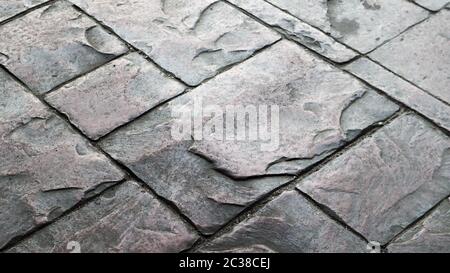 Concrete or cobblestone gray paving slabs or stones for the floor. Pavement in the city. Large gray paving tiles close up Stock Photo