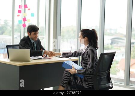 Young employers in black suits shaking hands during a meeting in the office. Pleasant atmosphere after a job interview. Stock Photo