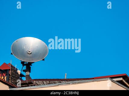 Satellite dish on the roof of the building against the blue sky. Technology. Place for text. Background image. Stock Photo