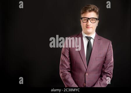 Portrait of law student with blond hair wearing glasses dressed in burgundy jacket, white shirt and black tie posing on isolated background with copy Stock Photo