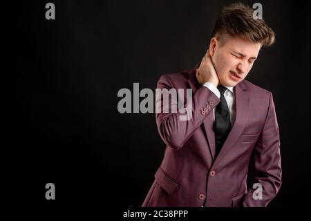 Law student with blond hair dressed in burgundy jacket, white shirt and black tie has sore throat posing on isolated black background with copy space Stock Photo
