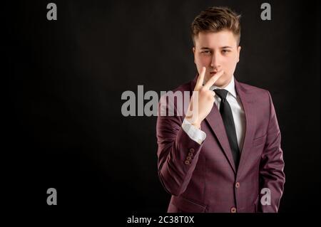 Pay attention or look at me concept law student with blond hair dressed in burgundy jacket, white shirt and black tie posing on isolated black backgro Stock Photo