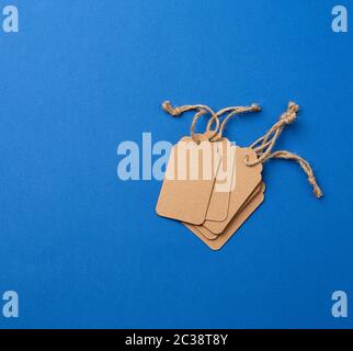 set of empty paper brown rectangular tags on a rope, price tags are on a blue trend background, top view Stock Photo