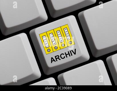 Yellow folders on computer keyboard showing Archive in german language Stock Photo
