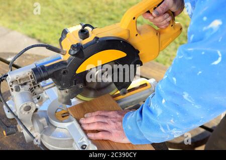 Man using chop saw to cut wooden flooring Stock Photo