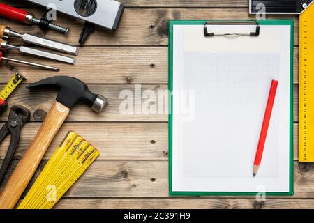 Top view to the carpenter's tools and notebook for notes on an antique wooden table. Construction industry, do it yourself. Wooden work table. Stock Photo