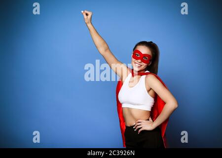Cheerful woman in superhero cloak holding arm raised Stock Photo