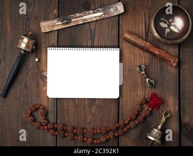 Copper singing bowl, prayer beads, prayer drum and other Tibetan religious objects for meditation and alternative medicine and open notebook on a brow Stock Photo